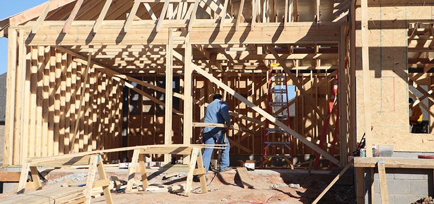 Man Carrying Lumber into House Under Construction